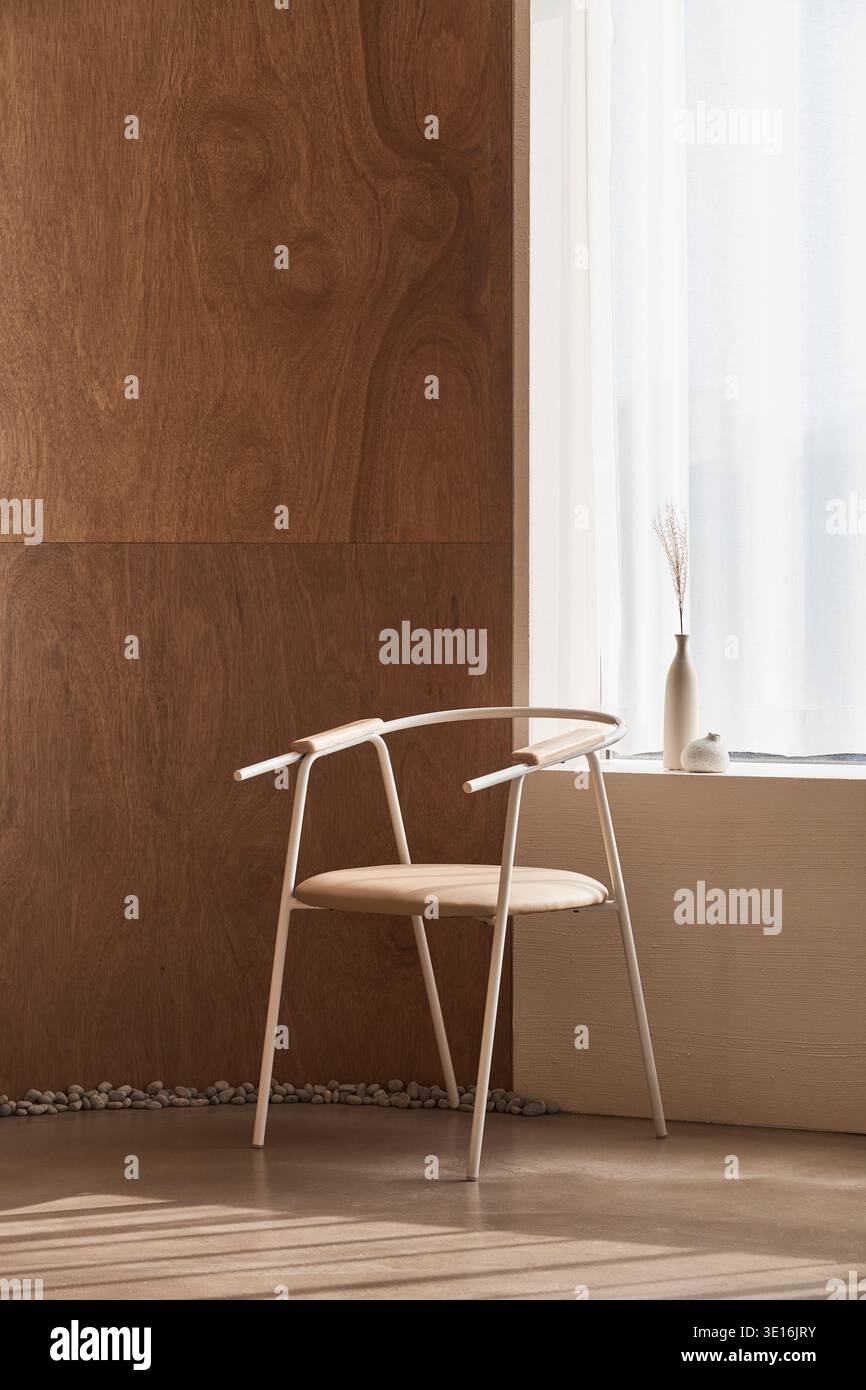 Holzstuhl neben einer sonnendurchfluteten Wand in einem ruhigen Raum. Stockfoto