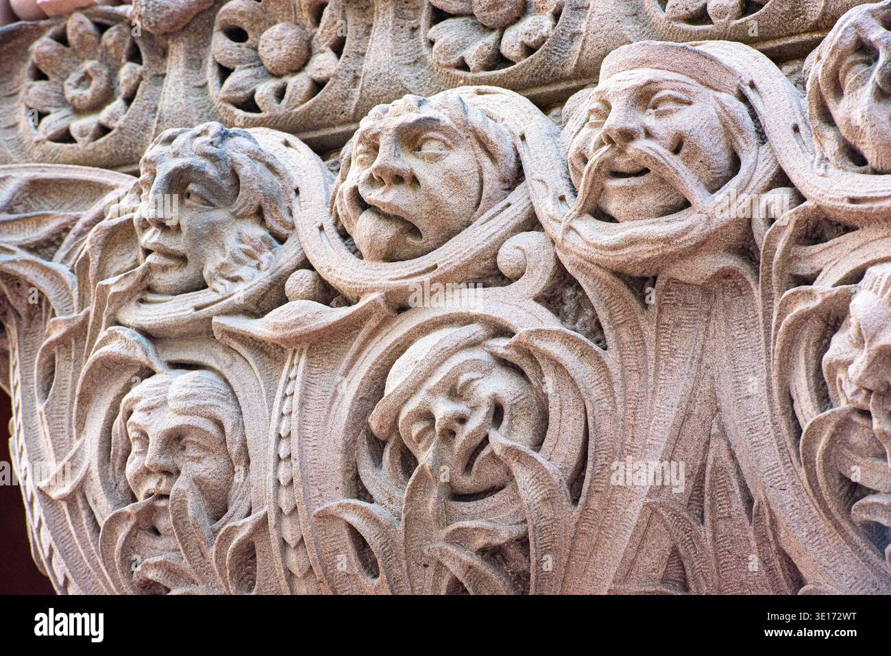 Kunstvolle Steinschnitzerei mit menschlichen Gesichtern und dekorativem Laub an einer historischen Gebäudefassade. Stockfoto