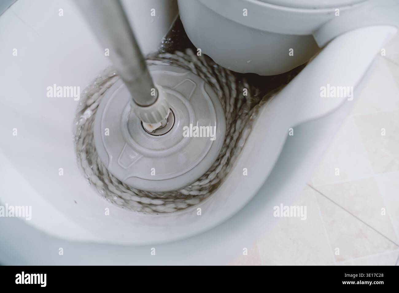 Blick von oben auf den Spin Mopp im weißen Eimer auf gefliestem Boden im modernen Badezimmer Stockfoto