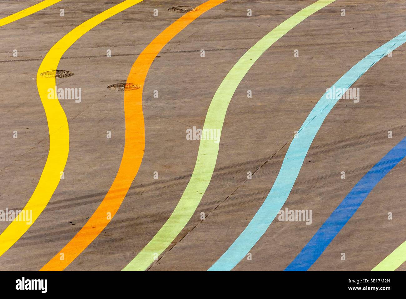 Eine leere Asphaltfläche ist mit bunten, geschwungenen Linien in Gelb, Orange, Grün, Blau und Braun verziert. erstellen eines lebendigen und dynamischen Musters Stockfoto