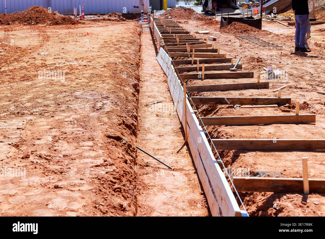 Die Arbeiter bereiten sich darauf vor, Betonfundamente mit Holzformen auf der Baustelle im ländlichen Raum zu gießen. Stockfoto