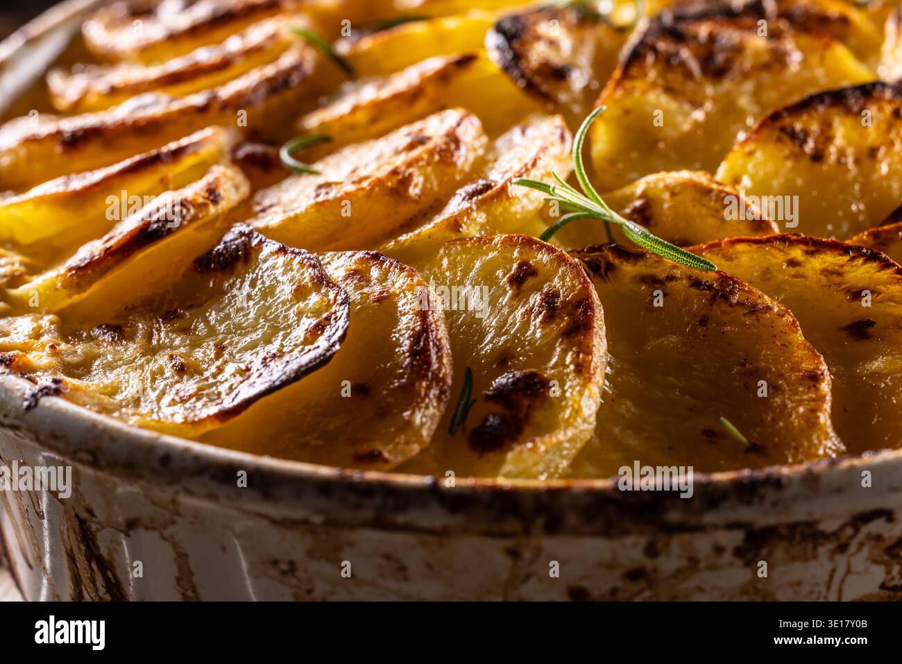 Goldbraune Gratin-Kartoffeln, ordentlich in einer weißen Keramikschale angeordnet und mit frischen Kräutern garniert. In der Slowakei ist dieses Gericht jedoch primari bekannt Stockfoto