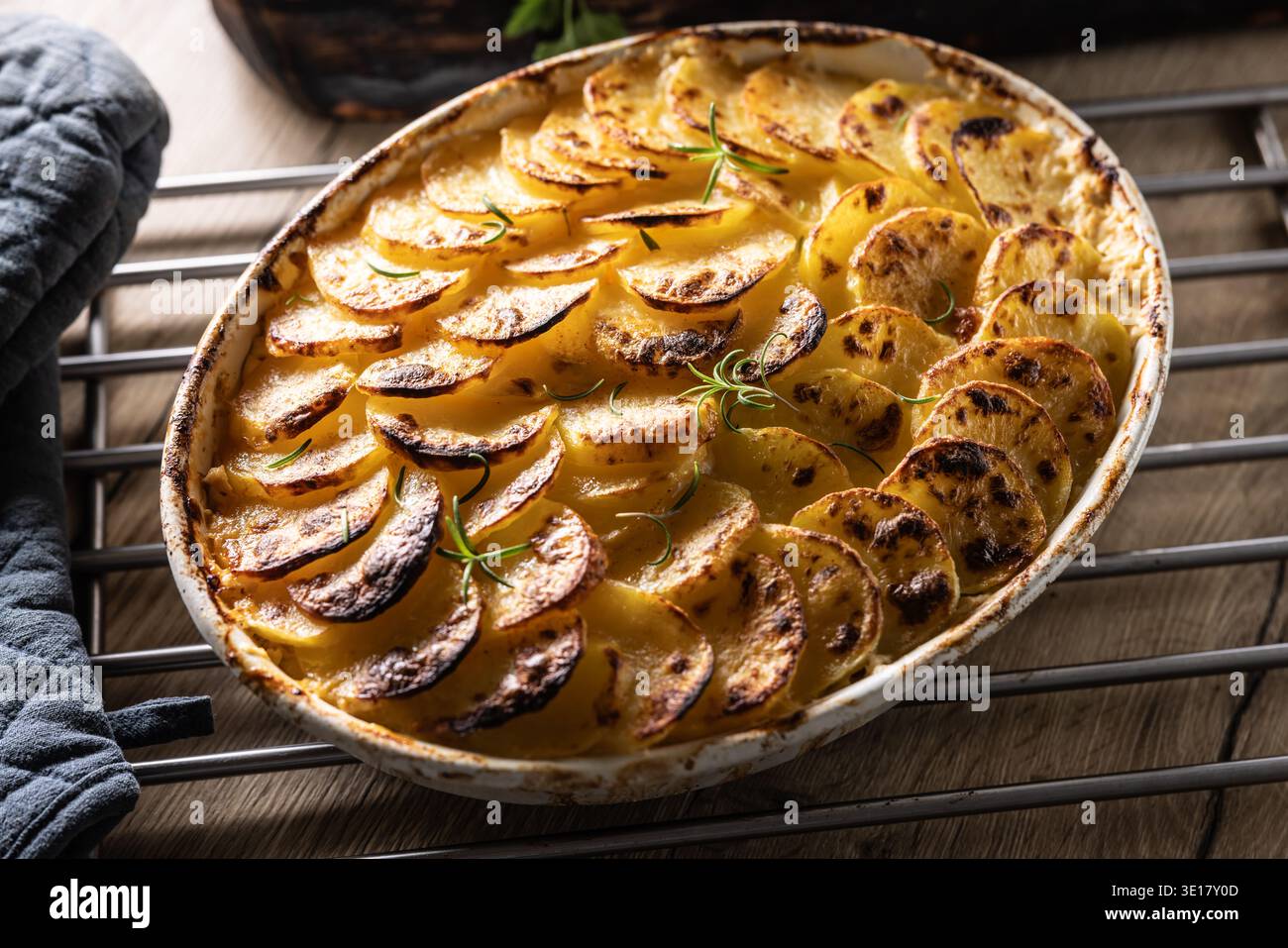 Goldbraune Gratin-Kartoffeln, ordentlich in einer weißen Keramikschale angeordnet und mit frischen Kräutern garniert. In der Slowakei ist dieses Gericht jedoch primari bekannt Stockfoto