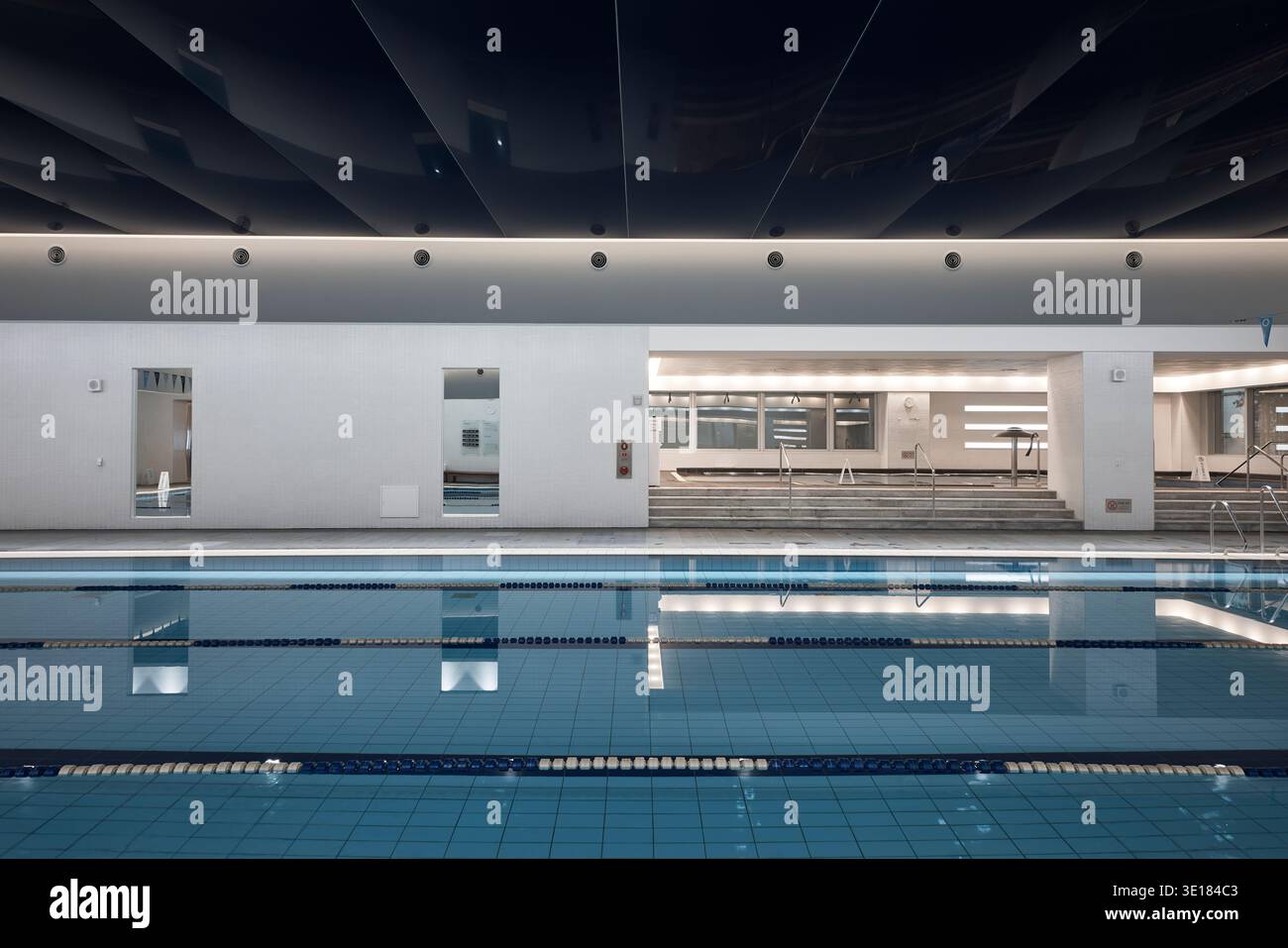 Hallenbad mit hellem Licht und reflektierendem blauem Wasser. Stockfoto