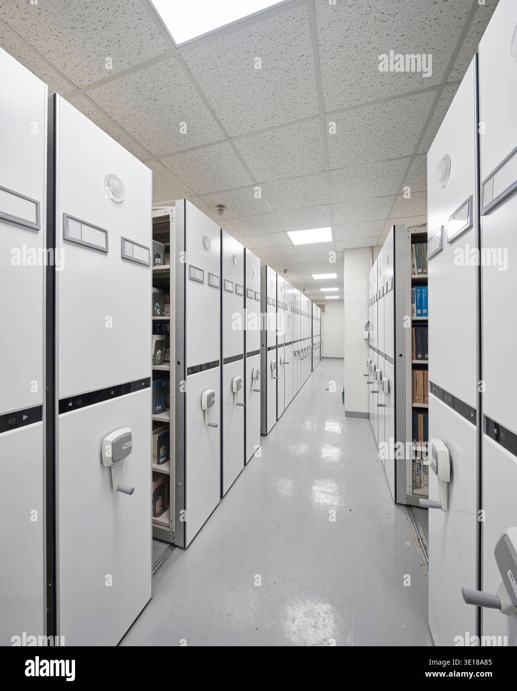 Archivlagergang mit kompakten Regalen und weißen Schränken. Stockfoto