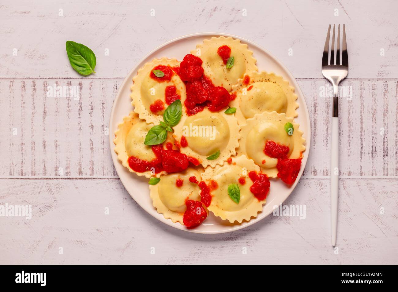 Ravioli mit Tomatensauce und Basilikum auf weißem Teller. Stockfoto