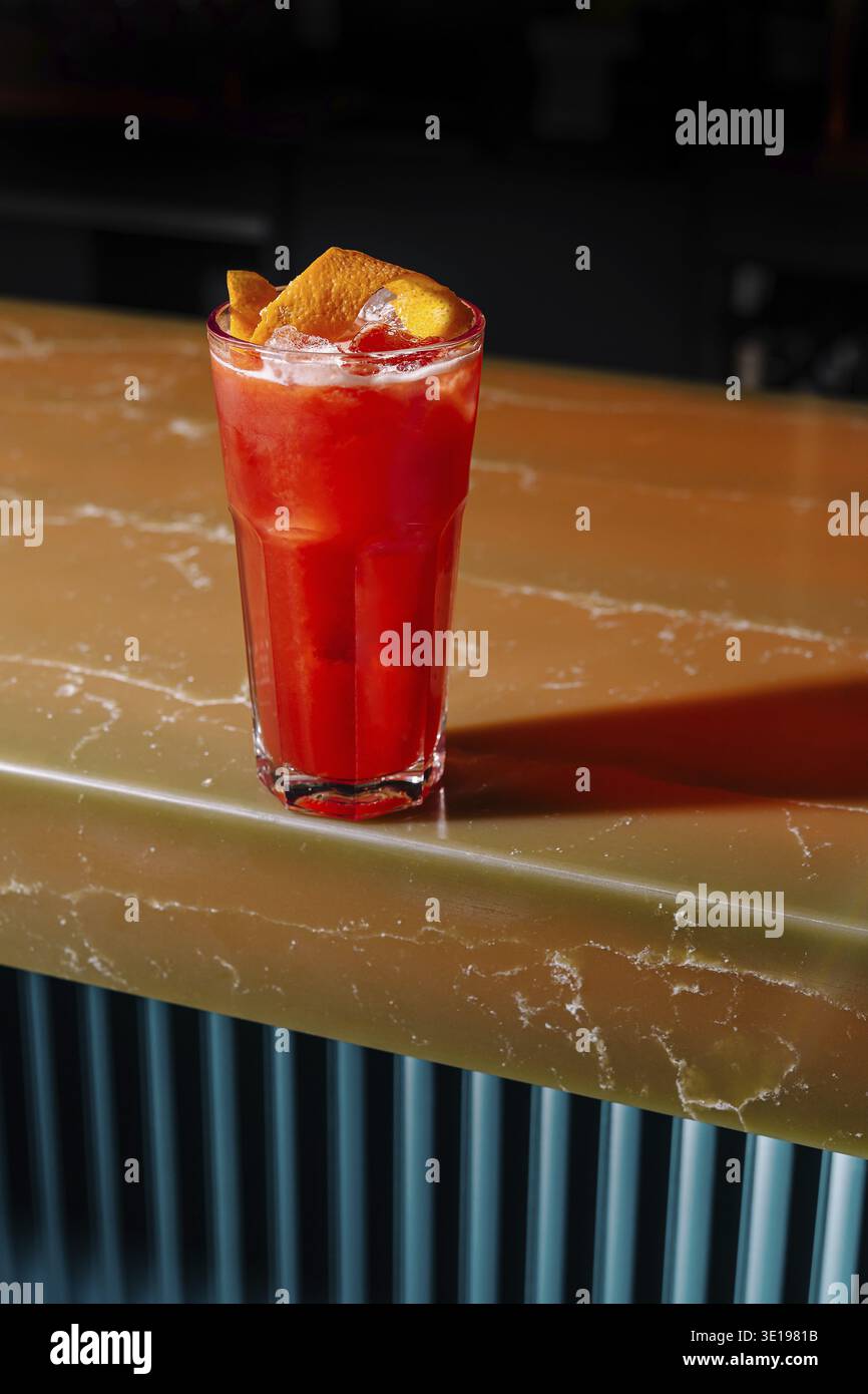 Vibrierender roter Cocktail mit Zitrusgarnitur, serviert auf einer Hochglanzbar Stockfoto