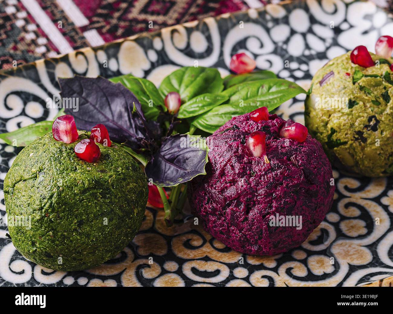 Exquisite vegane Vorspeise auf einem gemusterten Teller, garniert mit Granatapfelkernen und frischem Basilikum Stockfoto