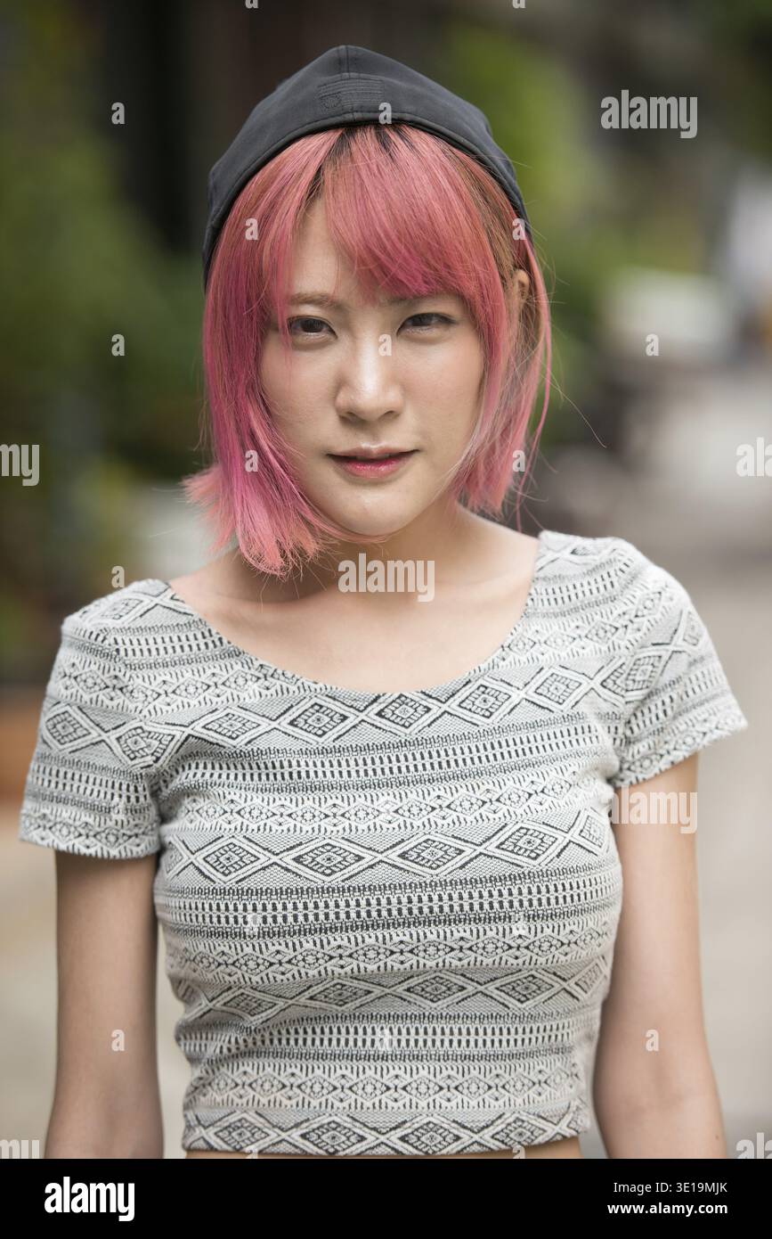 Porträt einer jungen, schönen asiatischen Frau mit rosa Haaren auf der Straße draußen Stockfoto