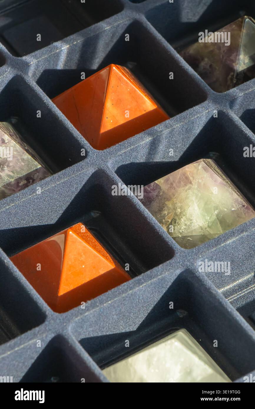 Nahaufnahme polierter Kristallpyramiden in einem Schaumband mit geometrischen Fächern. Sonnenlicht hebt Texturen, Farben und Minera hervor Stockfoto