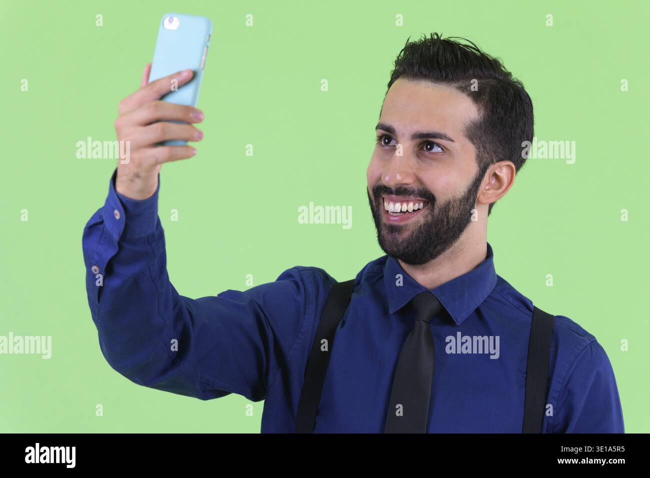 Studio-Aufnahme eines jungen gutaussehenden, bärtigen persischen Geschäftsmannes vor grünem Hintergrund Stockfoto
