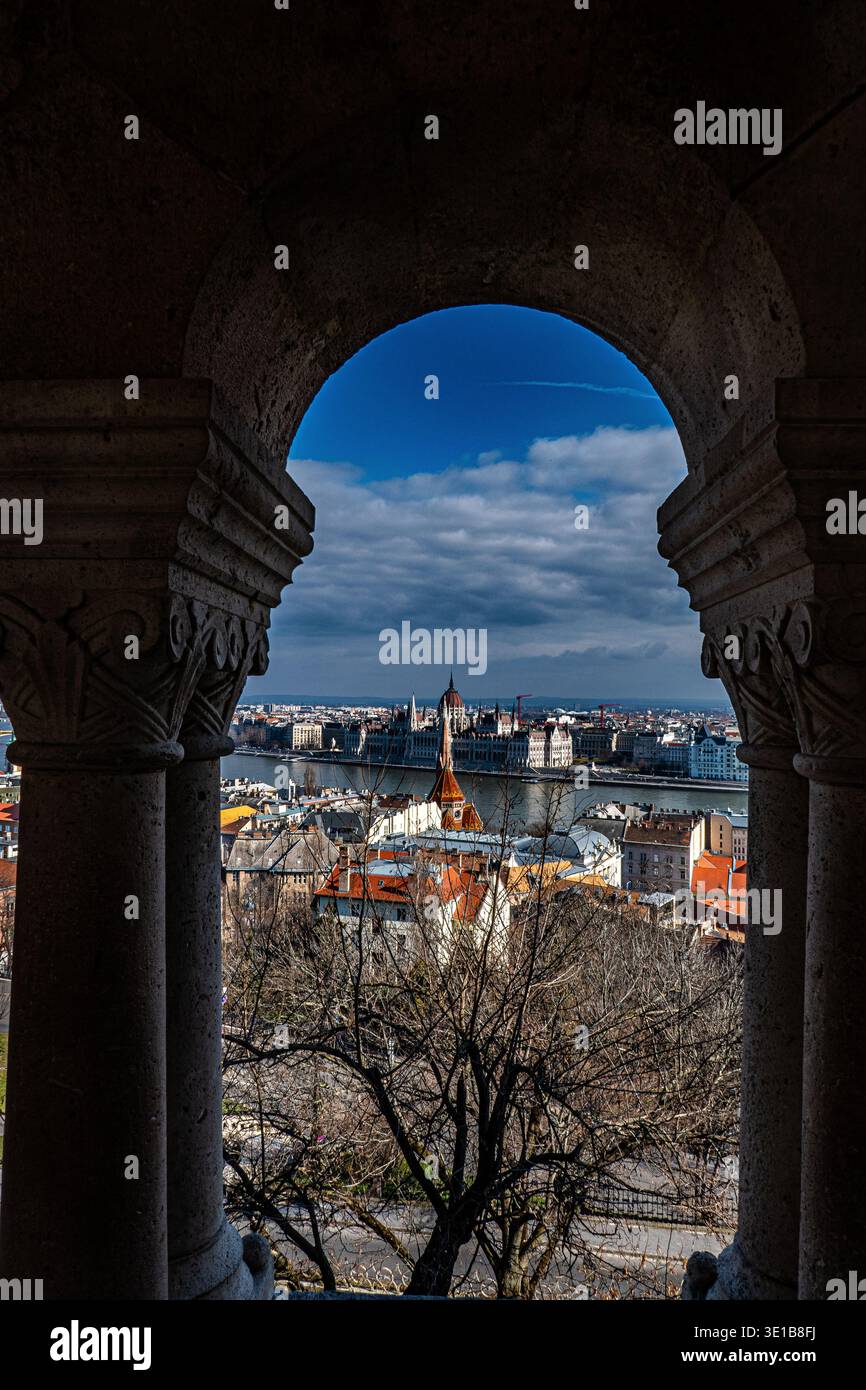Blick auf das ungarische Parlamentsgebäude und die Donau durch den kunstvollen Steinbogen der Fischerbastei, Budapest, Ungarn Stockfoto