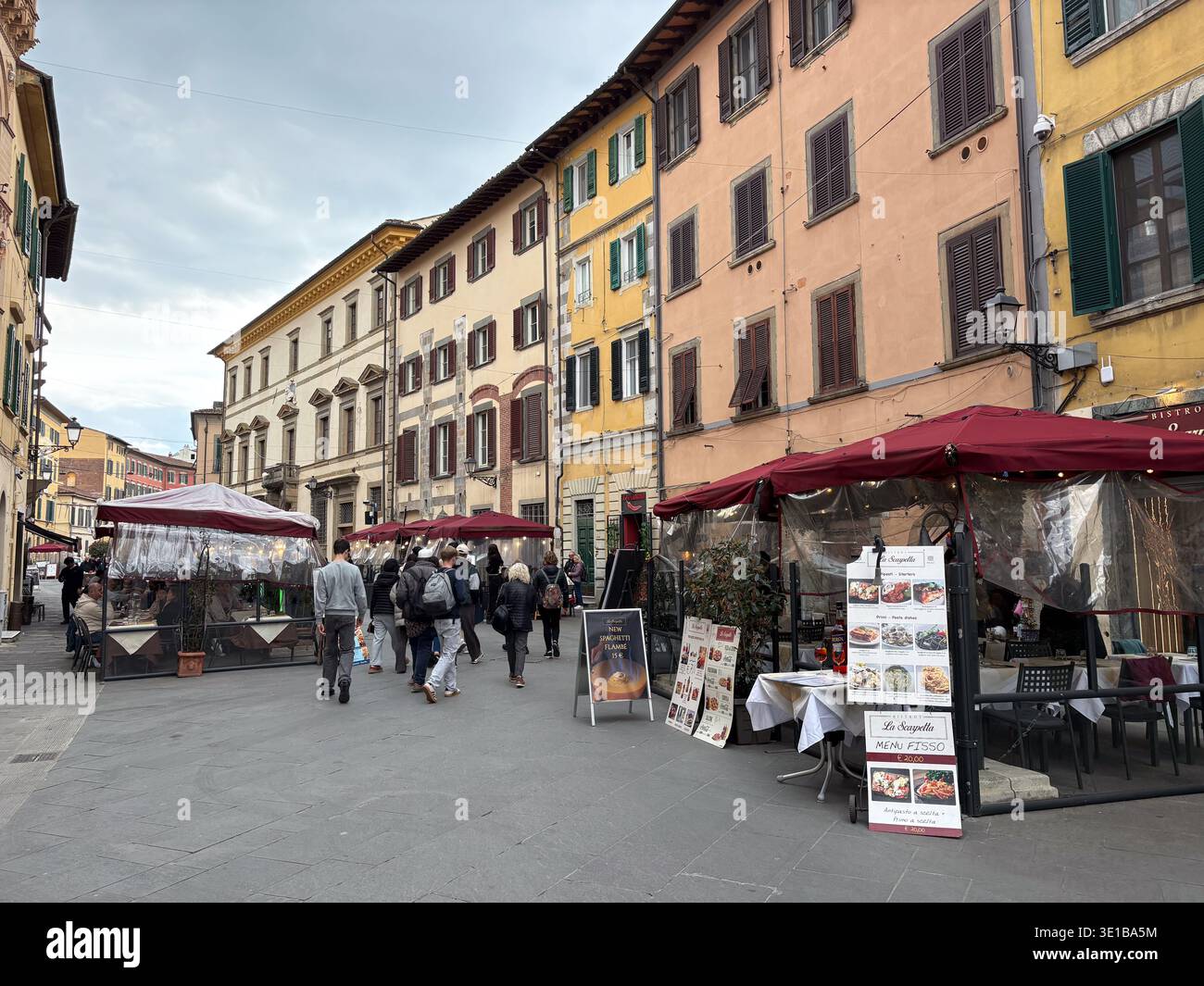 Sitzbereich des Restaurants Via Santa Maria. Historische Gebäude, Pisa, Italien. Touristen, die an temporären Restaurants im Freien vorbeilaufen. Stockfoto