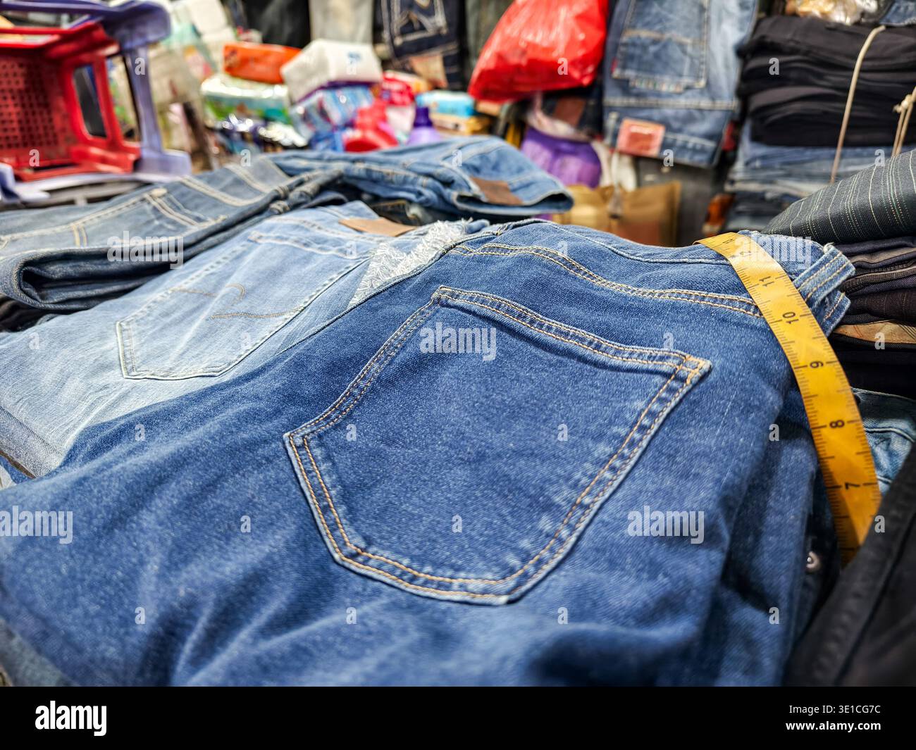 Nahaufnahme einer blauen Jeans mit gelbem Maßband über die Taille des oberen Paares in der gestapelten Ausstellung auf dem Central Market, Phnom Penh Stockfoto