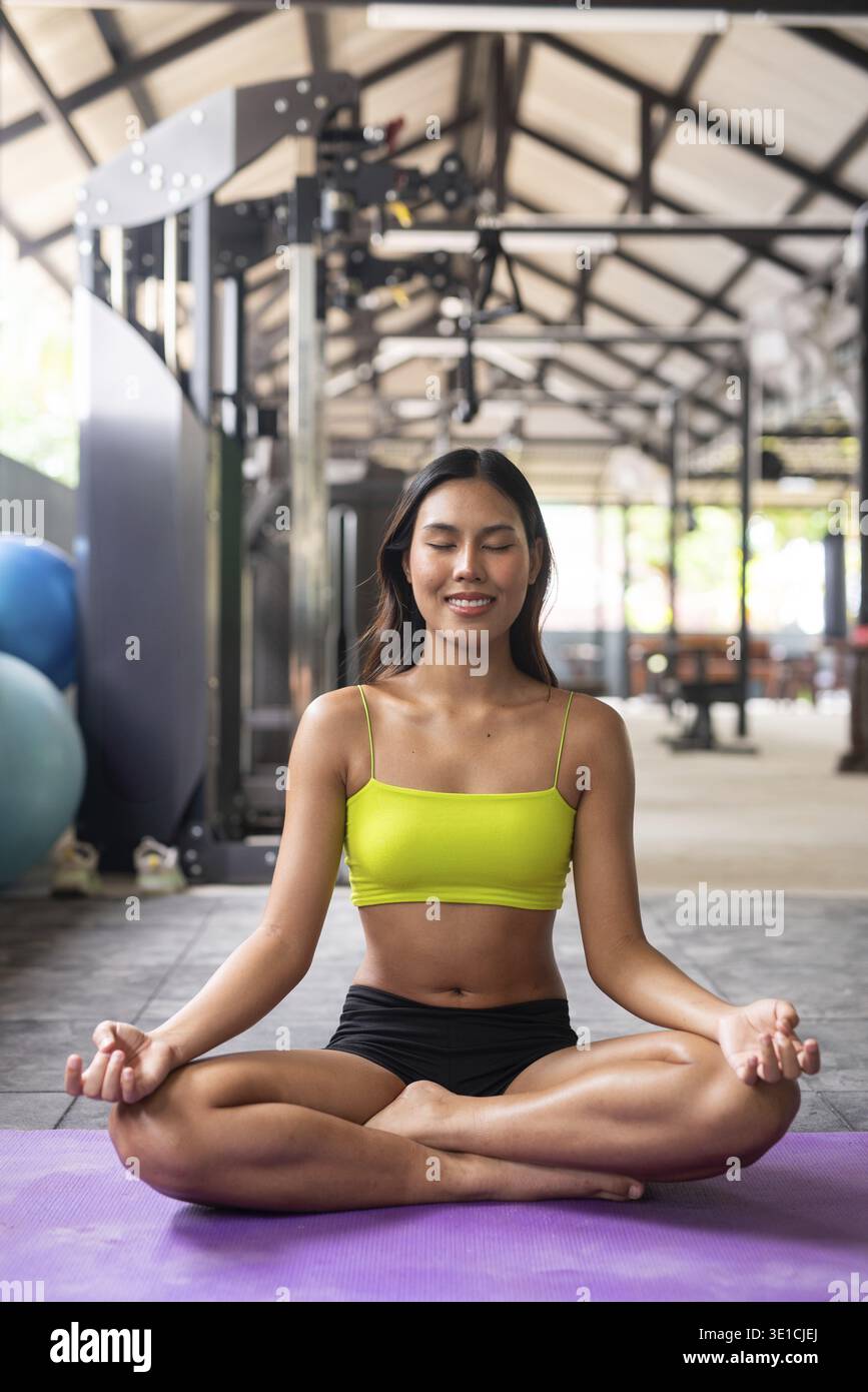 Junge, schöne asiatische Frau im Fitnessstudio, die Yoga macht Stockfoto