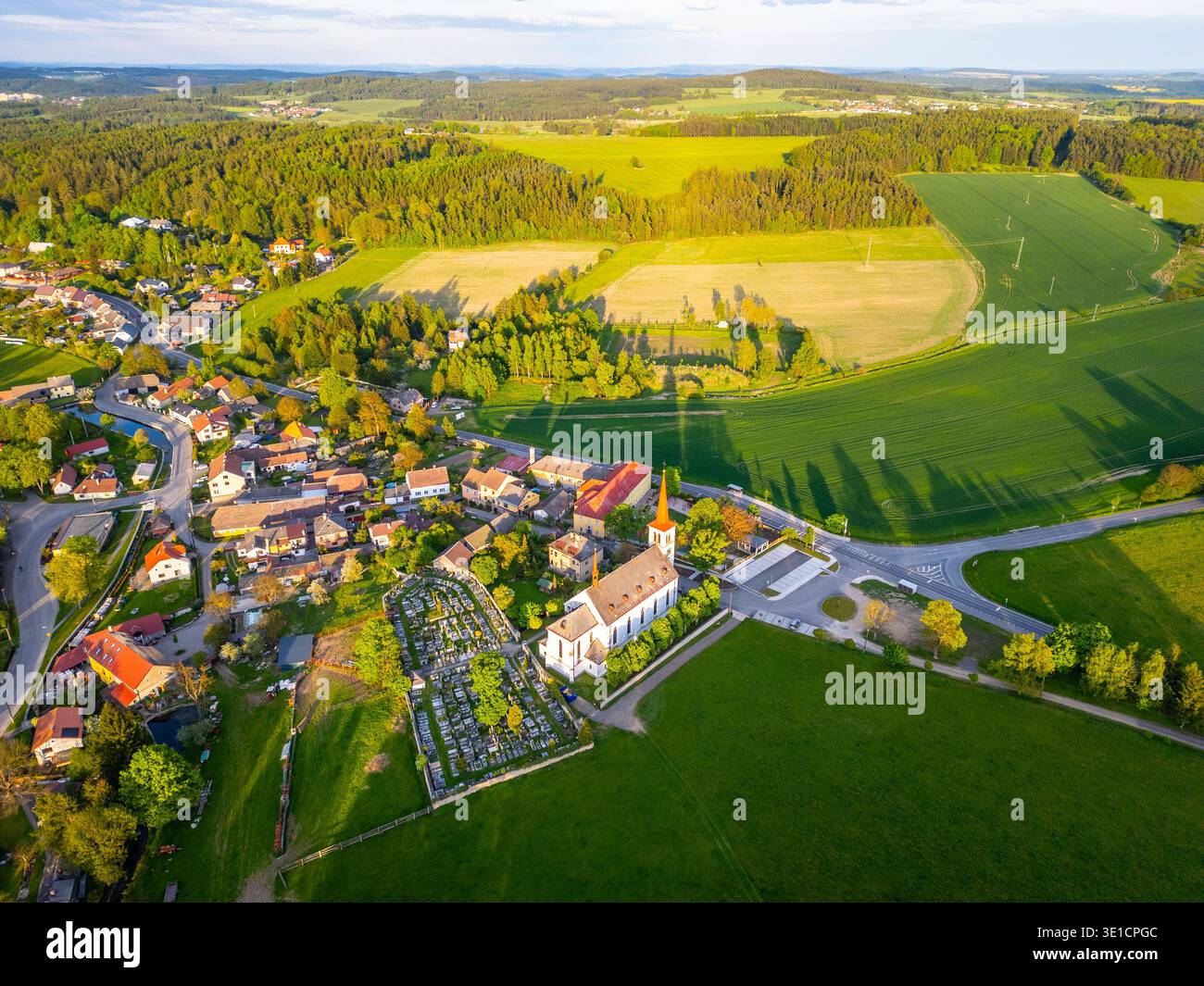 Bohutin Town bietet bezaubernde Architektur und grüne Landschaften von oben. Felder erstrecken sich bis in die Ferne, während die historische Kirche einen prominenten Platz unter den Wohngebieten hat. Stockfoto