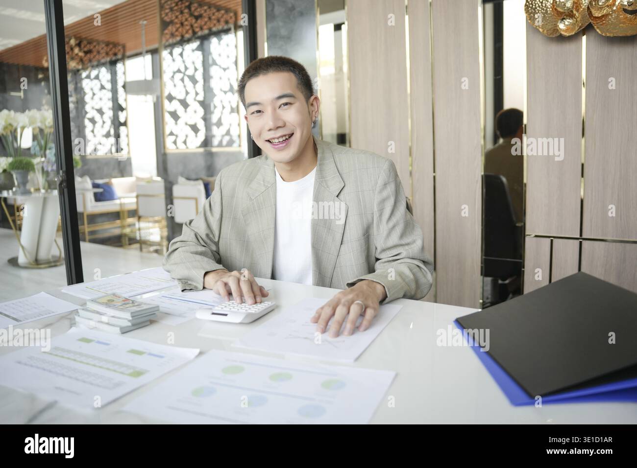 Lächelnder junger asiatischer Geschäftsmann im modernen Büro. Gutaussehender asiatischer Mann glücklich und freundlich während der Arbeit Erfolg Job Stockfoto