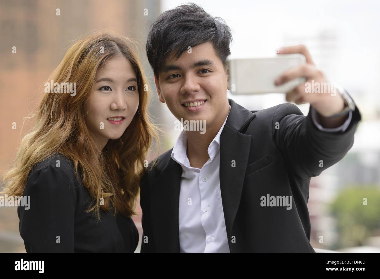 Porträt eines jungen asiatischen Geschäftsmannes und einer jungen asiatischen Geschäftsfrau zusammen in der Stadt draußen Stockfoto