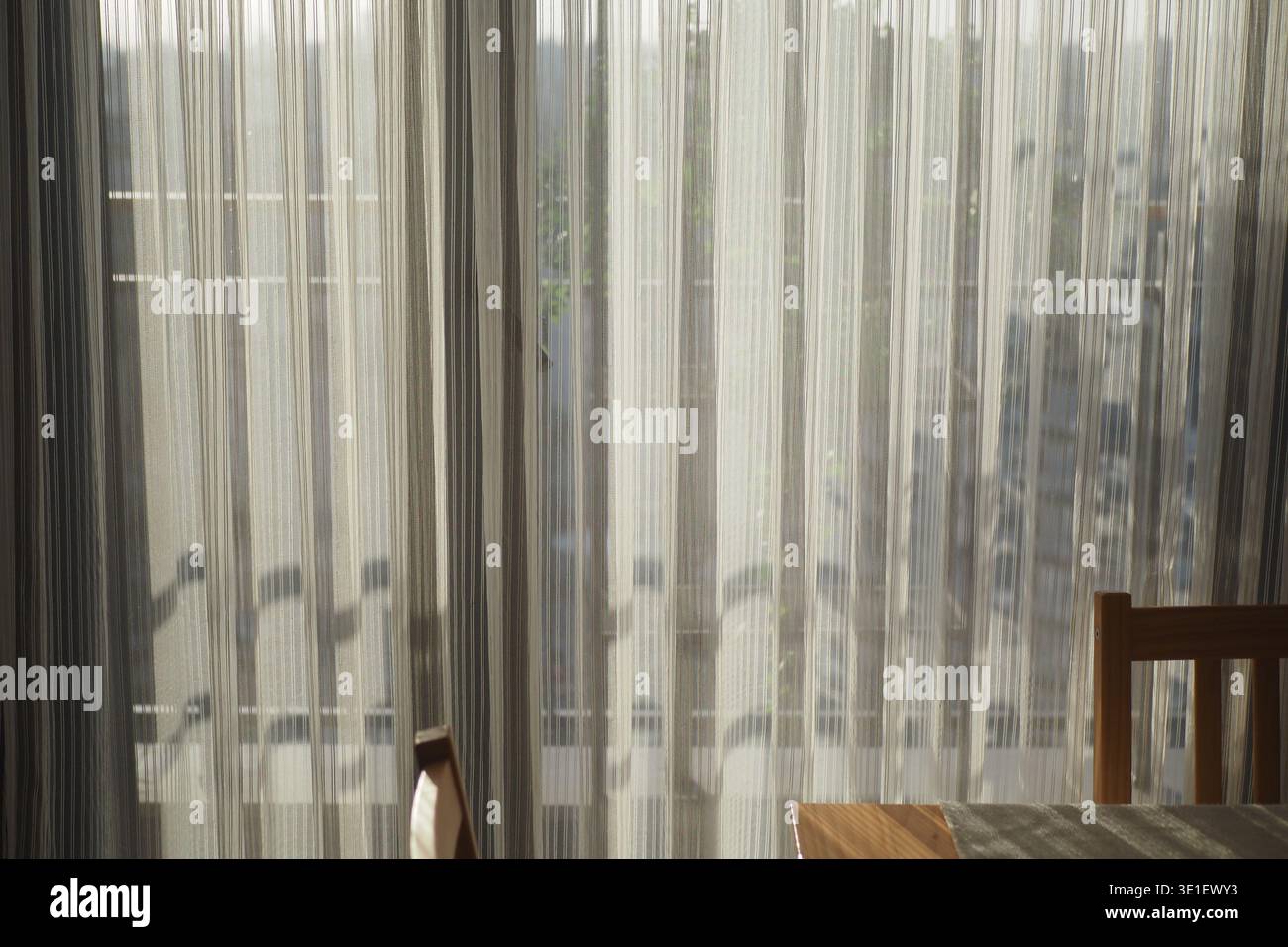 Vorhänge filtern das Sonnenlicht in einem ruhigen Raum am Fenster Stockfoto