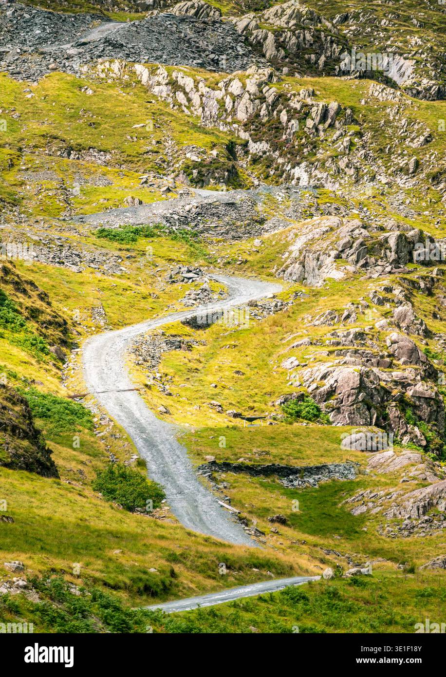 Dramatische Landschaft mit steiler, kurviger Straße, die einen felsigen Cumbrian Berg hinaufführt, vom Honister Pass Parkplatz, an einem warmen, sonnigen Sommertag. Stockfoto