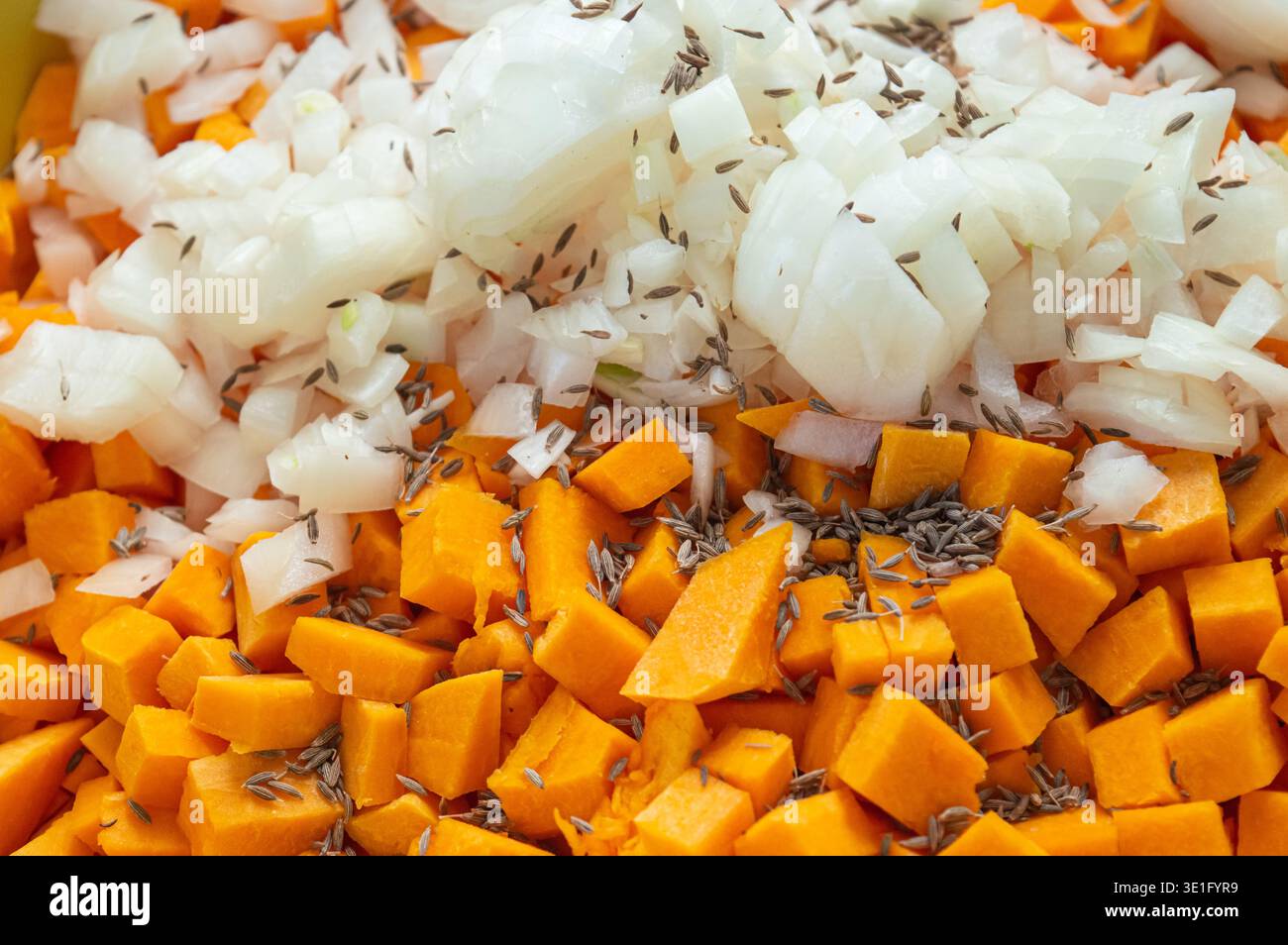 Kürbiswürfel und Zwiebeln in Gewürzen. Textur von Kürbiswürfeln mit Zwiebeln und Gewürzen zum Füllen von Kürbiskuchen. Hochwertige Fotos Stockfoto