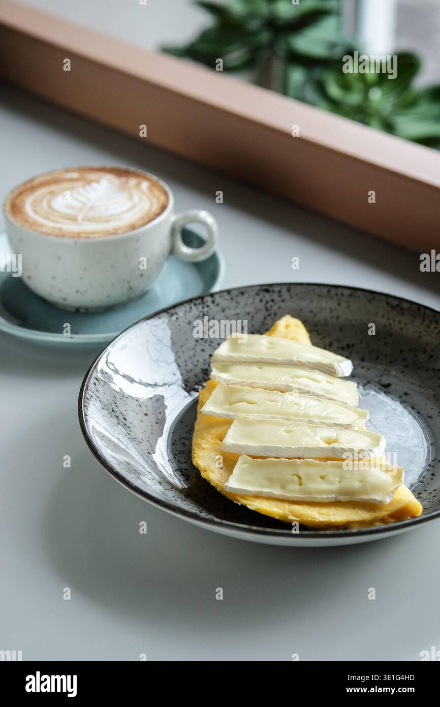Gemütlicher Morgen Mit Dampfendem Latte Und Käse. Helle Fensterszene Mit Cremigem Kaffee Und Handwerklichem Brot Stockfoto