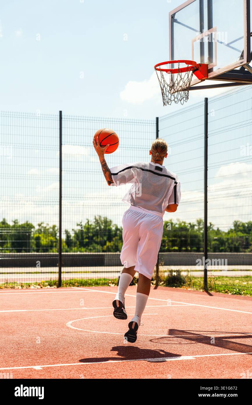 Aktive junge Frau, die im Sommer Basketball auf einem Outdoor-Stadtplatz spielt, urbanen Sport und gesundes Lifestyle-Konzept Stockfoto