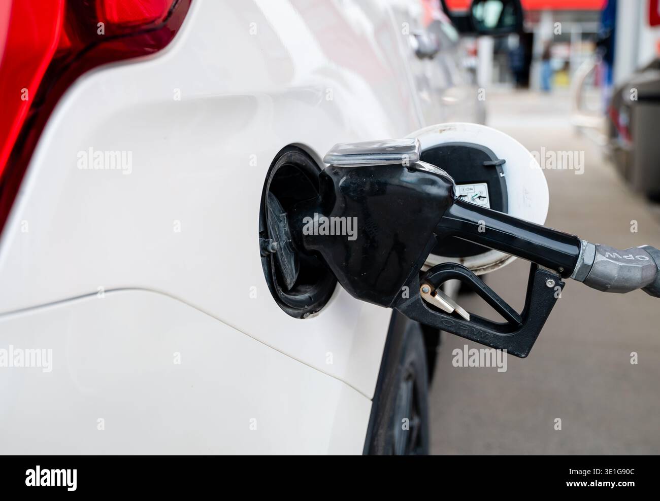 Nahaufnahme der Kraftstoffdüse der Gaspumpe, die den Tank eines Fahrzeugs füllt. Stockfoto