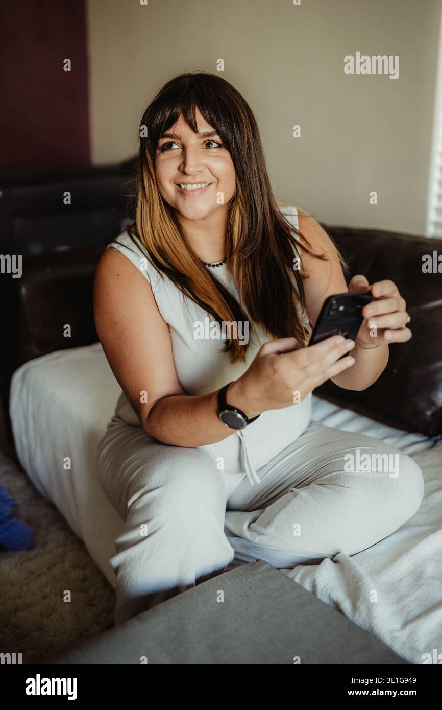Frau, die von zu Hause aus mit ihrem Telefon arbeitet Stockfoto