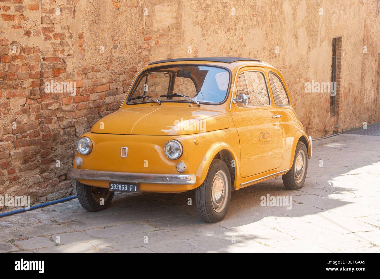 Baccoleno, Italien, 05.07.2026, klassischer gelber Oldtimer in einer historischen europäischen Stadt in der Nähe einer alten Ziegelmauer. Weiches Sonnenlicht, Retro-Stil und Stockfoto