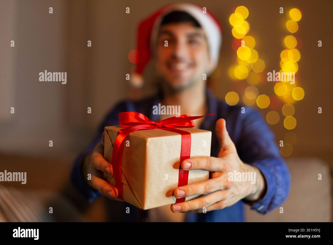 Ein Mann, der weihnachtsgeschenk gibt, weihnachtsmütze trägt Stockfoto
