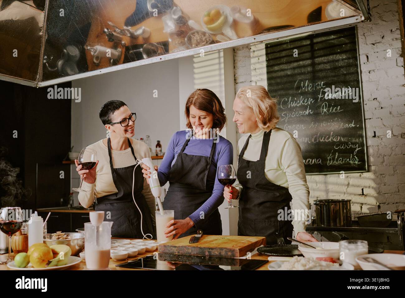 Drei weiße Frauen mittleren Alters, die an Kochkurs teilnehmen und Essen vorbereiten Stockfoto