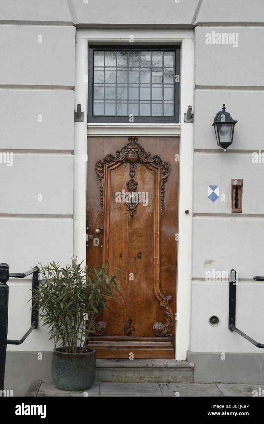 Kunstvoll geschnitzte Holztür mit Spiegelfenster in einem traditionellen Gebäude Stockfoto