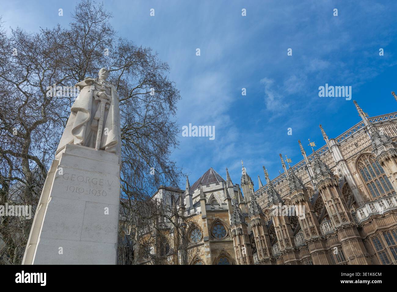 Statue von König Georg V. im Old Palace Yard mit der gotischen Architektur der Westminster Abbey und der Kapelle Heinrich VII. Im Hintergrund Stockfoto