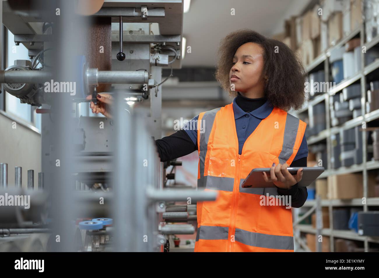 Afroamerikanische Frau, Arbeiter in der Metallindustrie, die ein Tablet für die Gerätediagnose und digitale Checklisten an der Produktionslinie verwendet. Stockfoto