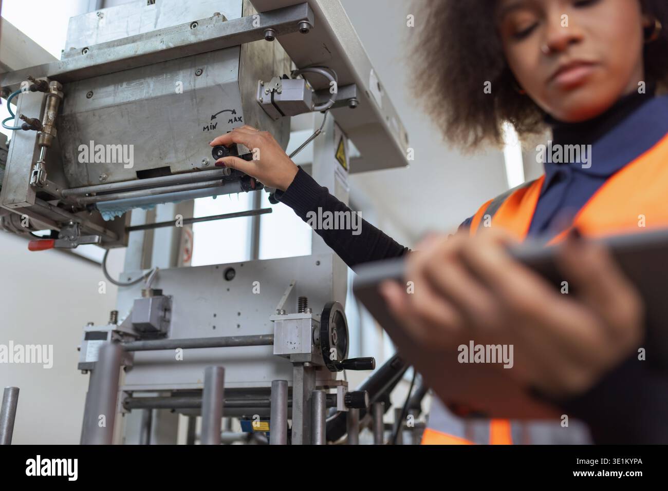 Afroamerikanische Frau, Arbeiter in der Metallindustrie, die ein Tablet für die Gerätediagnose und digitale Checklisten an der Produktionslinie verwendet. Stockfoto