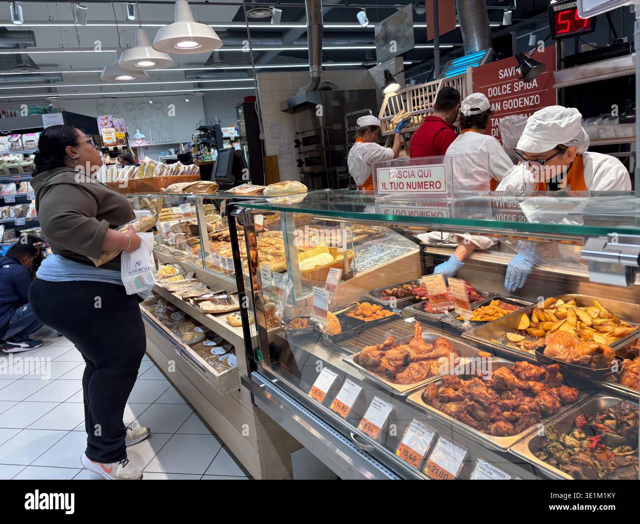 Feinkosttheke im Supermarkt von CONAD. Florenz, Italien. Die Angestellten servieren zubereitete Speisen und Backwaren an die Käufer, die in der Schlange stehen. Stockfoto