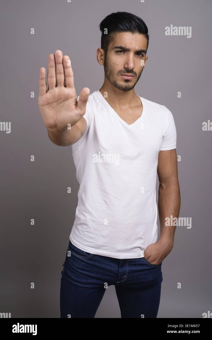 Studio shot der jungen schönen persischen Mann gegen grauer Hintergrund Stockfoto