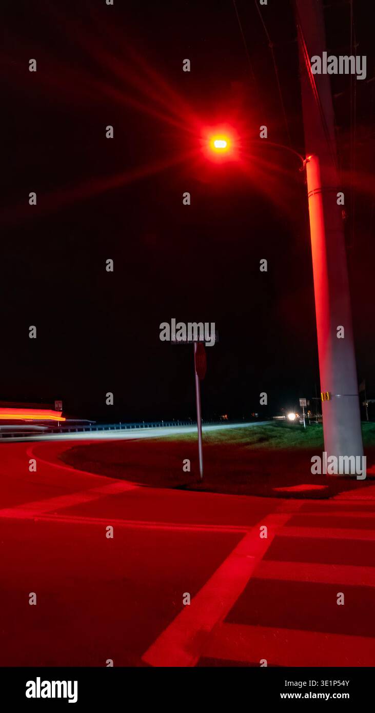 Vertikale Nachtperspektive einer leuchtenden roten Straßenlaterne und Lichtwege in den Florida Keys Stockfoto