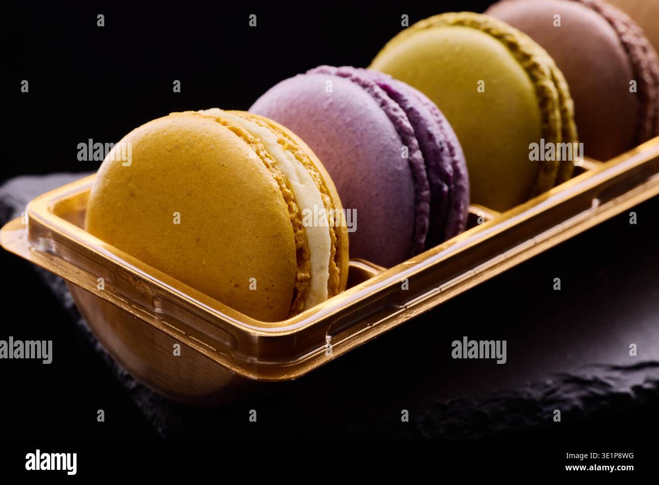 Bunte Macarons leckere Kekse auf schwarzem Hintergrund. Traditionelles französisches Dessert, Gourmet-Konditorei Stockfoto