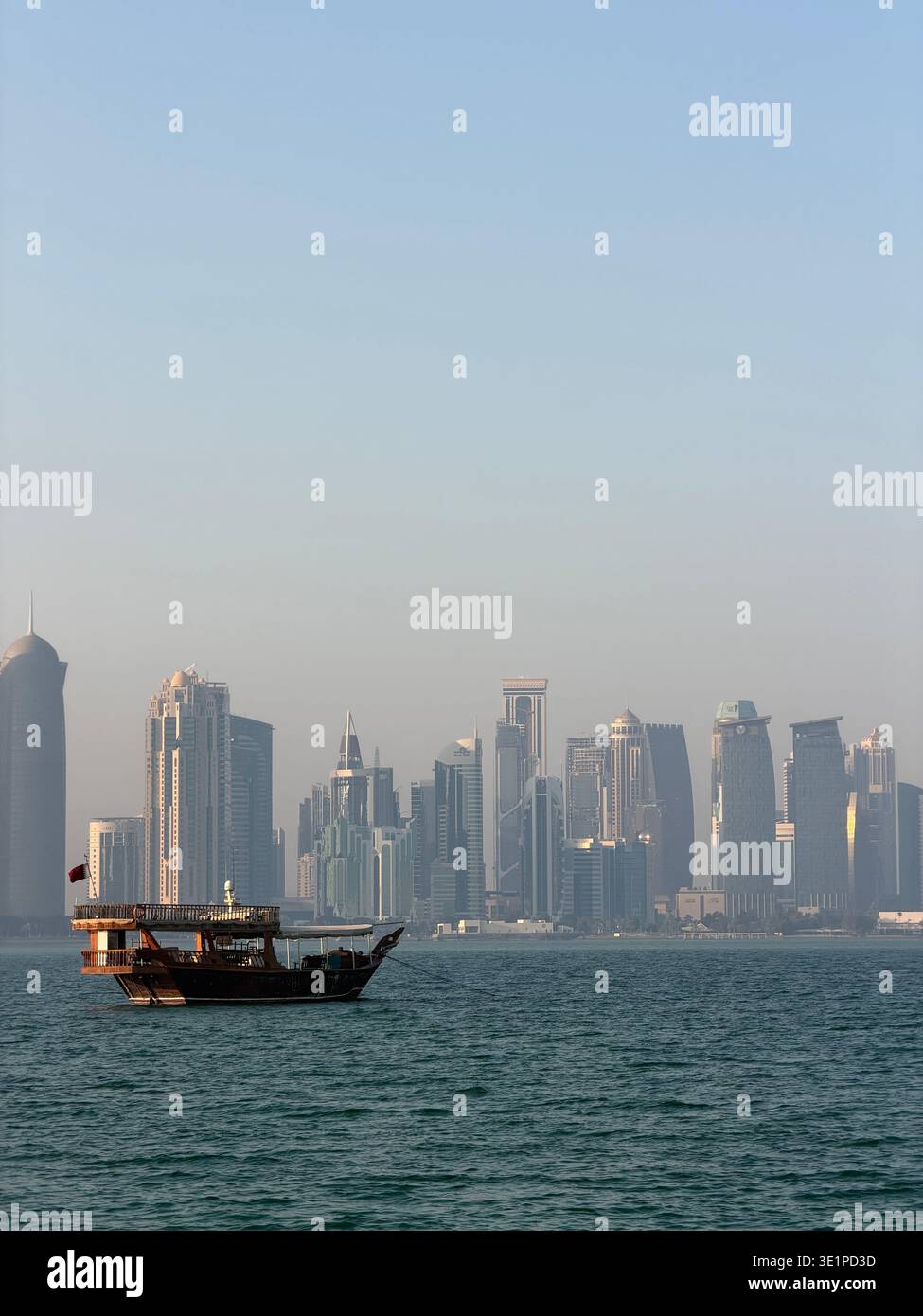 Traditionelles Dhow-Boot am Arabischen Golf mit moderner Skyline von Doha, Katar im Hintergrund. - Smartphone-aufgenommenes Stockfoto