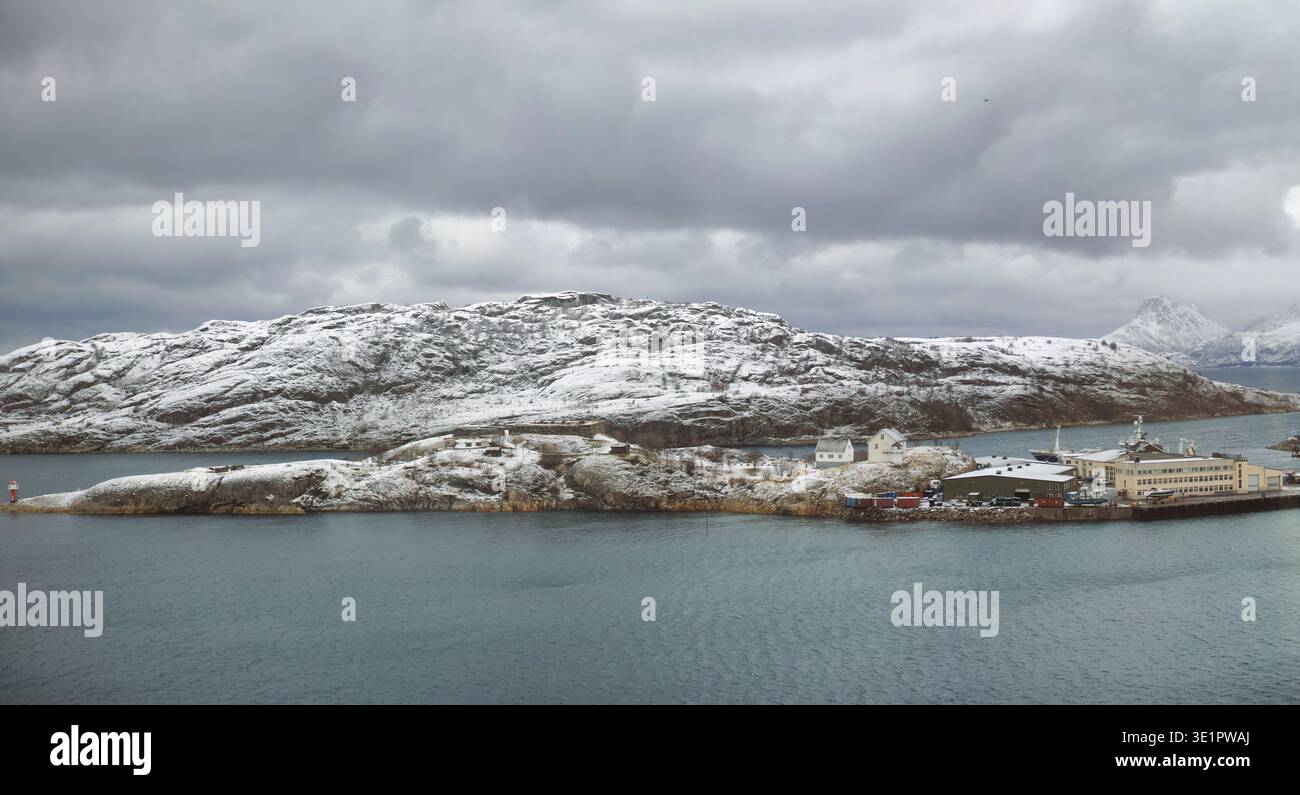Hintergrund, Berg und Meer mit Hafenstadt im Winter für ästhetische Landschaft oder bewölkten Morgen. Bewölkter Himmel, Meer und Schnee mit Seehafen im Freien Stockfoto