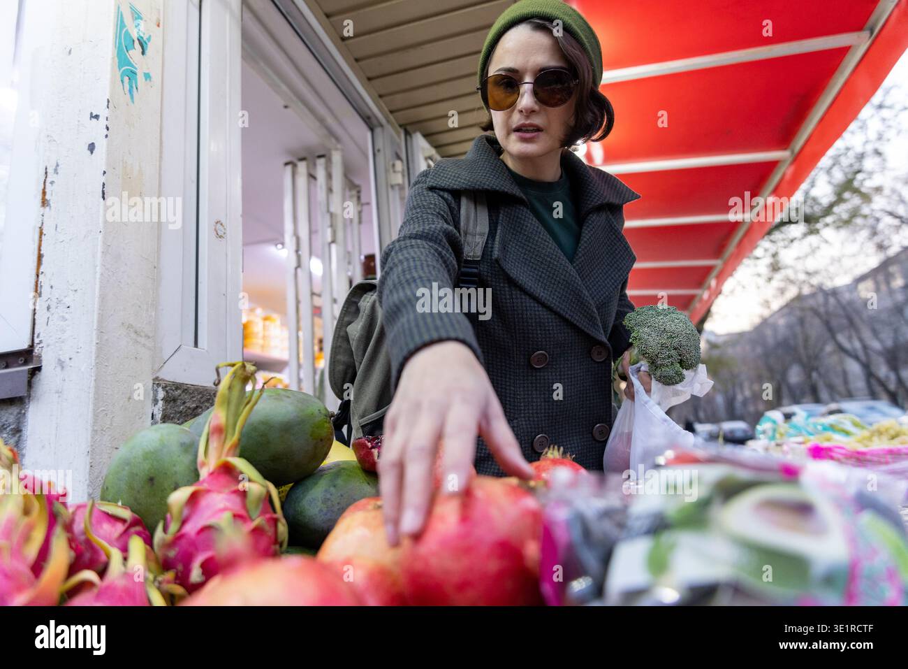 Frau pflückt Granatäpfel am Obststand Stockfoto