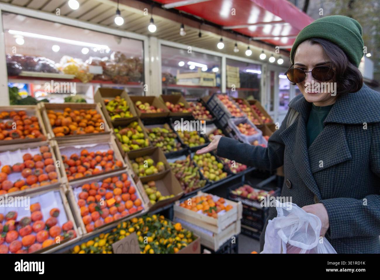 Lächelnde Frau, die Obstsorten auf dem Markt präsentiert Stockfoto