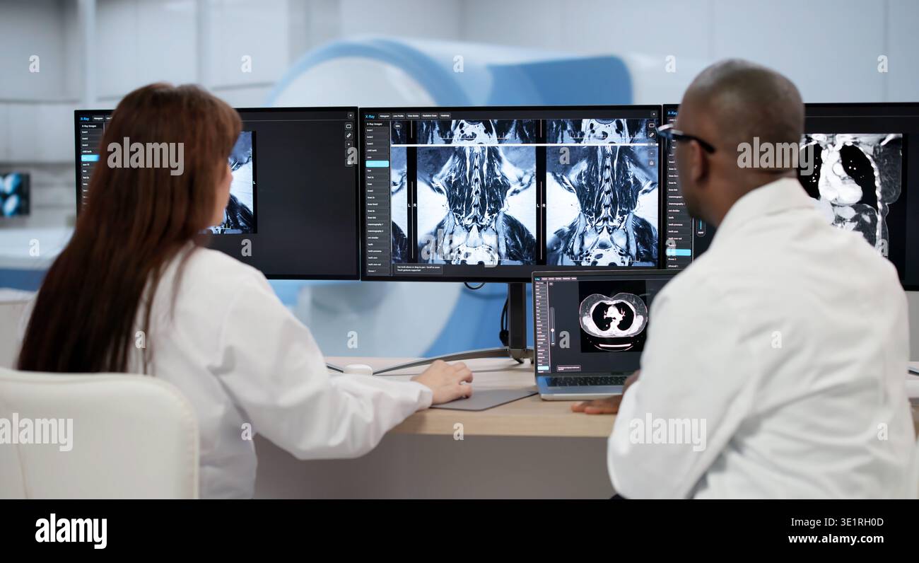 Zwei Ärzte untersuchen Röntgenbilder sorgfältig auf Einem Computerbildschirm und besprechen Behandlungsoptionen Stockfoto