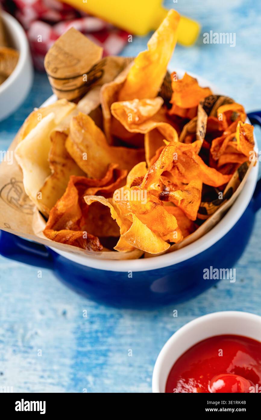 Knusprige Gemüsechips serviert mit Ketchup auf blauem Tisch Stockfoto