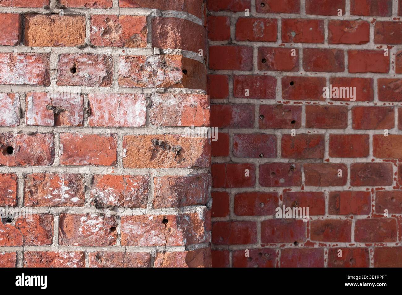Nahaufnahme der strukturierten roten Ziegelwand mit Mörtelfugen und verwitterter Oberfläche, die architektonische Details und Mängel zeigt Stockfoto