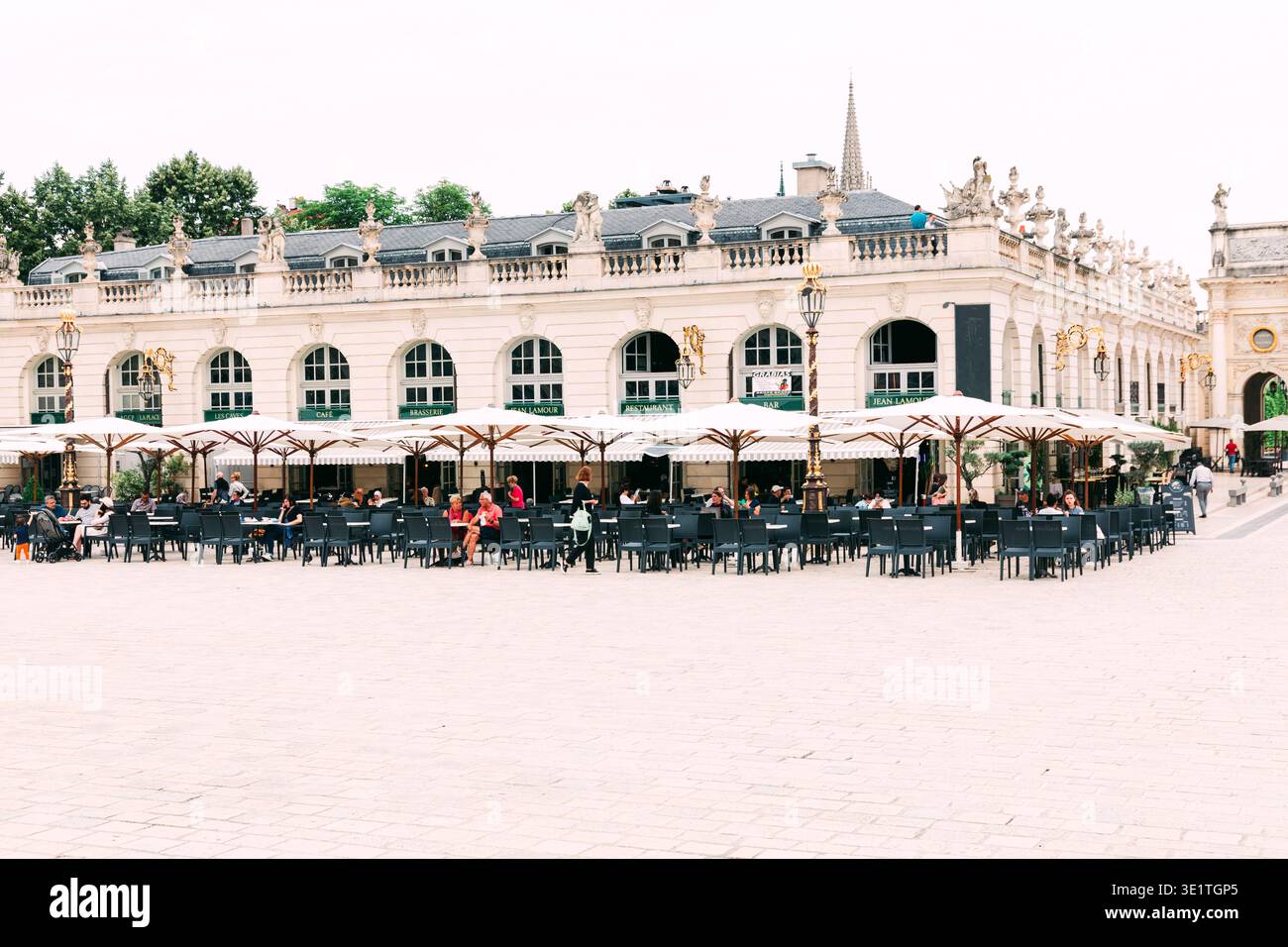 Elegantes französisches Barockgebäude mit Café-Terrasse im Freien, kunstvollen Skulpturen und Bogenfenstern am Place Stanislas in Nancy Stockfoto