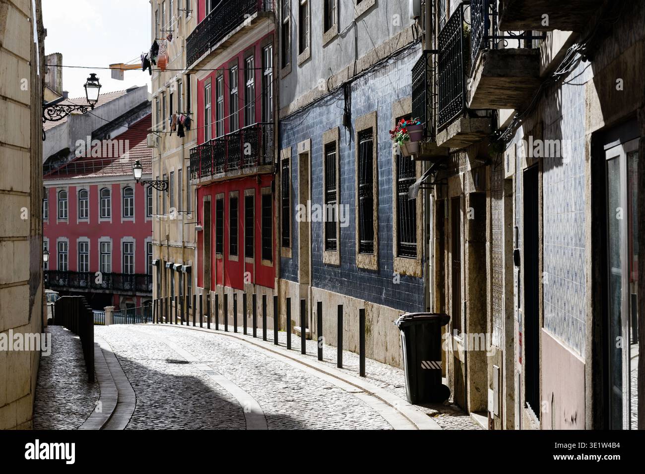 Enge, kopfsteingepflasterte Straße in Lissabon, Portugal, gesäumt von bunten, alten Gebäuden im historischen Viertel Alfama. Stockfoto