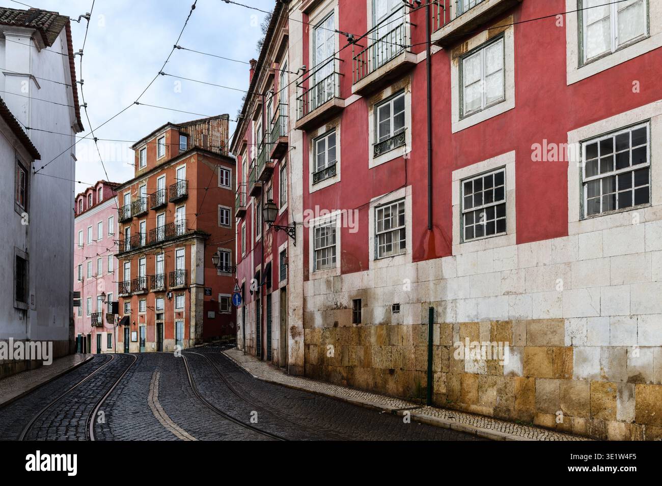 Enge, kopfsteingepflasterte Straße in Lissabon, Portugal, gesäumt von bunten, alten Gebäuden im historischen Viertel Alfama. Stockfoto